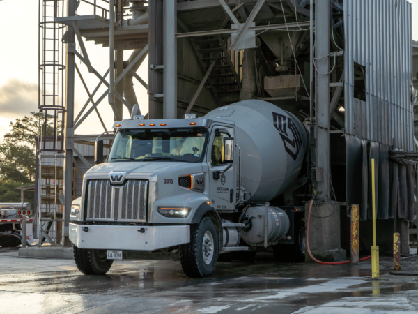 Cement mixer truck collecting ready mix from silo.