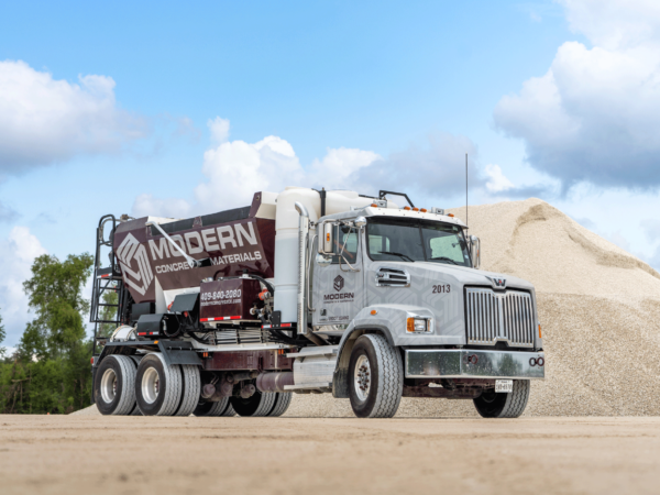 Volumetric mixer truck in front of material in daylight.