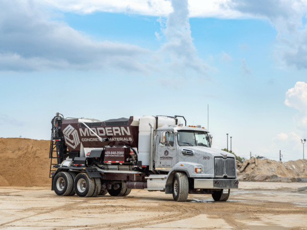 Volumetric mixer truck at the plant, with partly cloudy sky in the background.