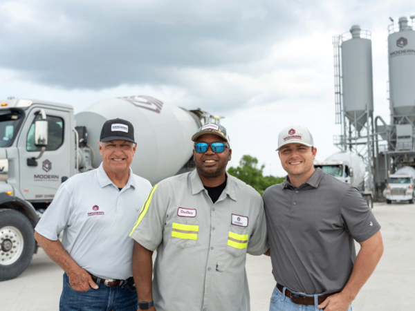 Modern team members standing in front of a cement truck.